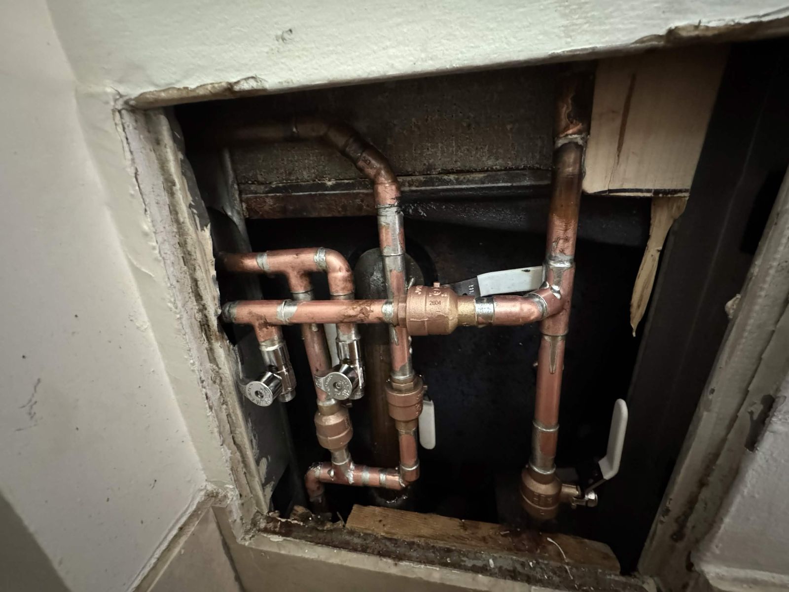 Copper water lines and shutoff valves behind an access panel.