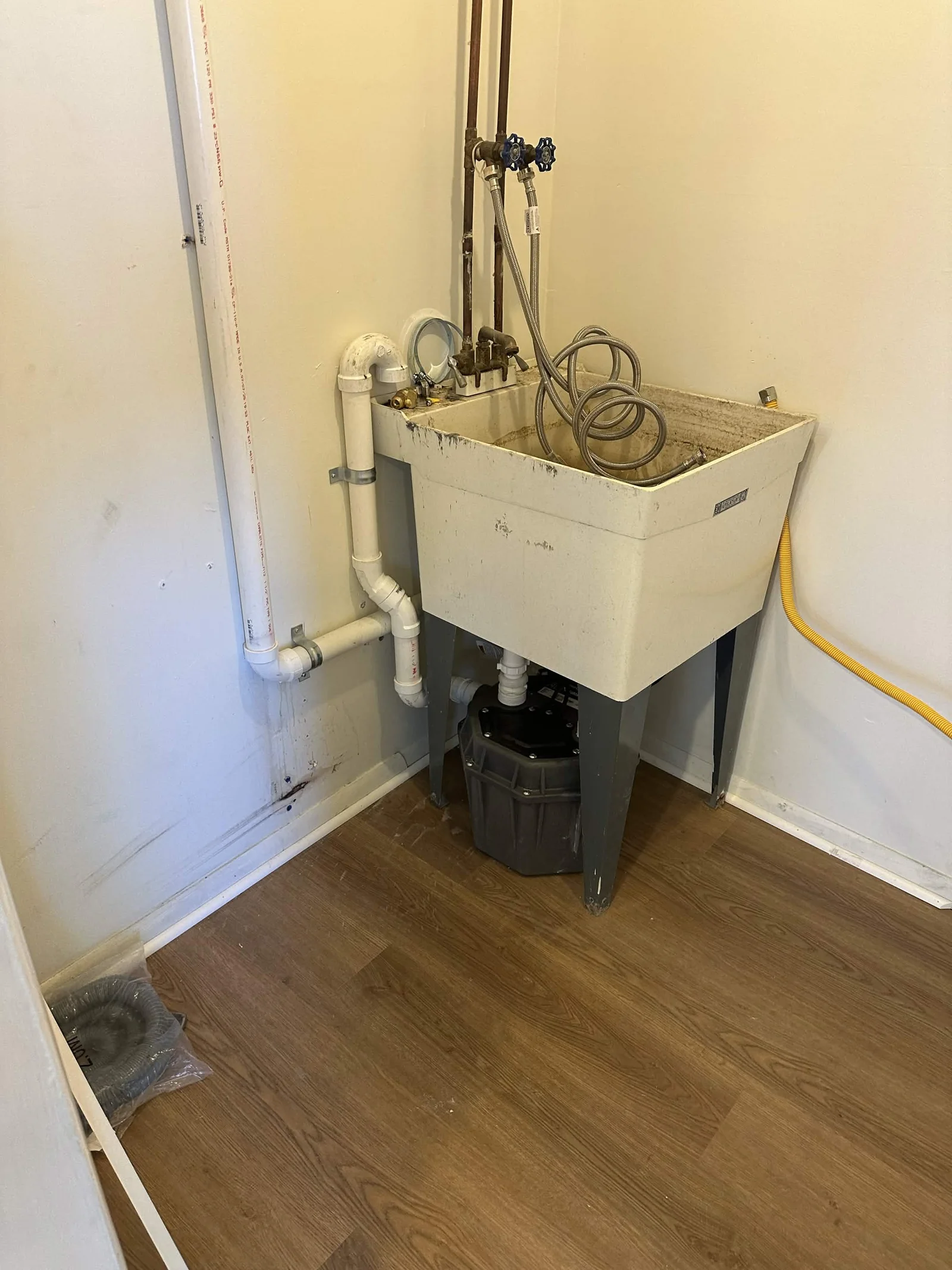 Basement laundry sink with a drain pump and connected piping.